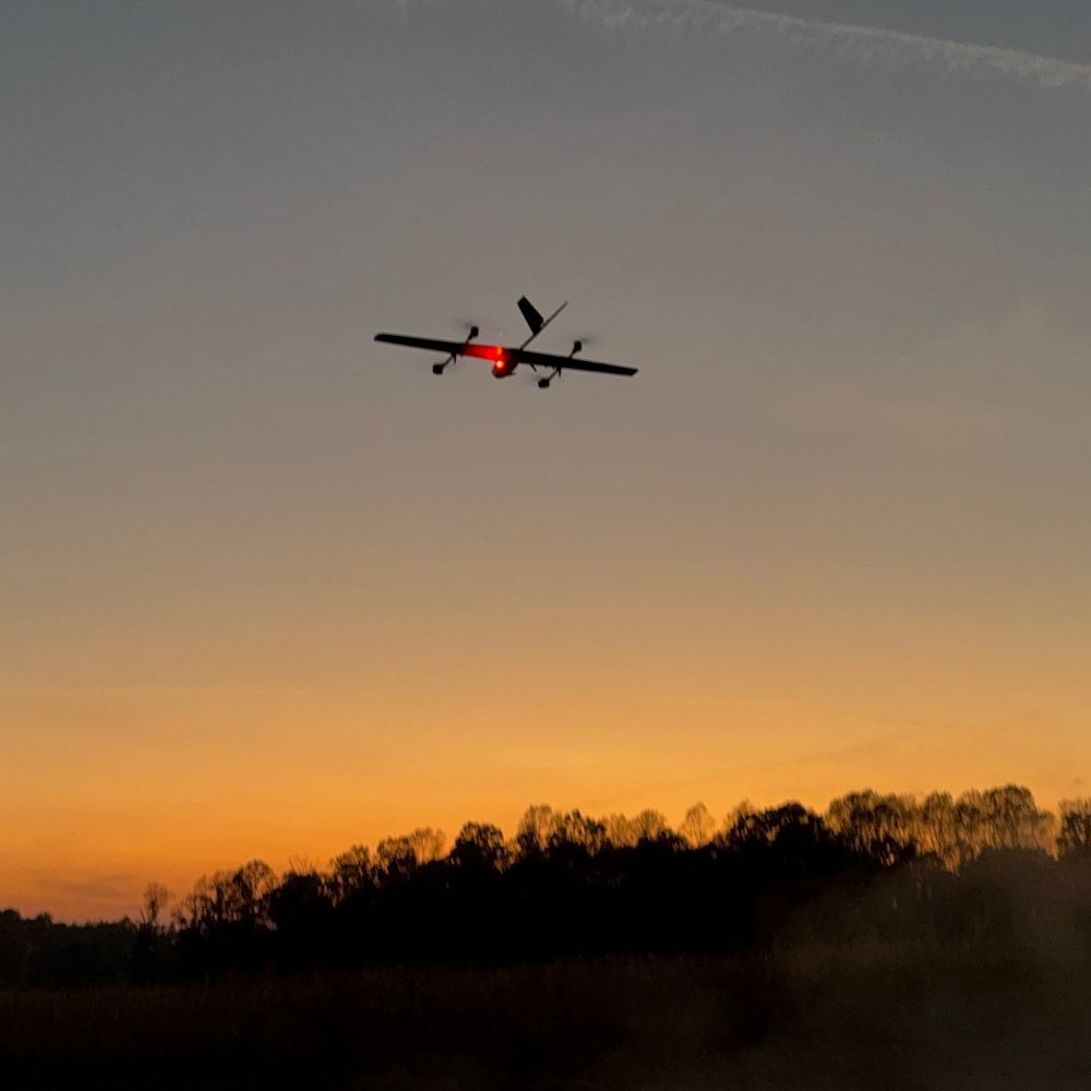 The WingXpand xRAI smart plane in flight at sunset over open terrain